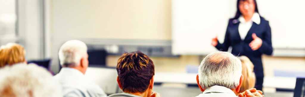 Photo of the back of adult students' heads as an instructor teaches